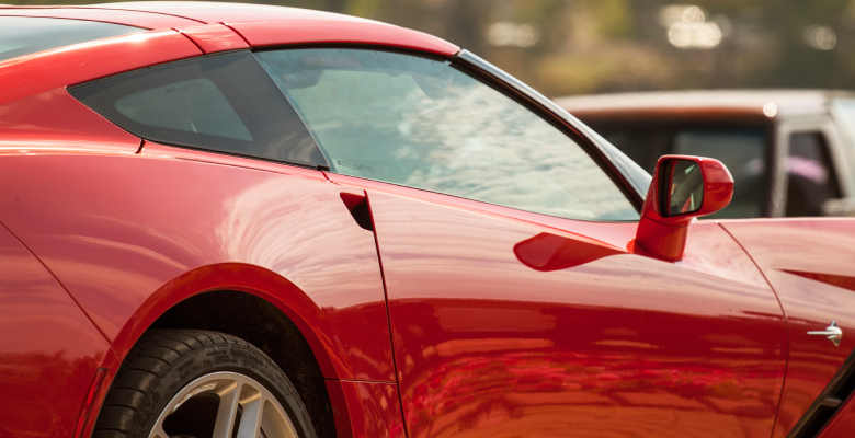Close up of red luxury European vehicle parked in street.